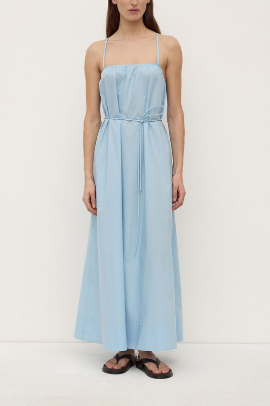Model wearing the maxi dress with the waist tie fastened, showing the straight neckline, gathered bodice and flowing skirt, full-length front view

