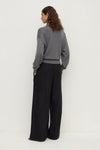 Back view of a model wearing black wide-leg pants, showing the relaxed shape, elasticated waistband and full-length legs.
