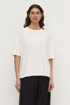 A woman wearing an antique white short-sleeve tee with a ribbed crew neckline and relaxed boxy fit, shown from the front.