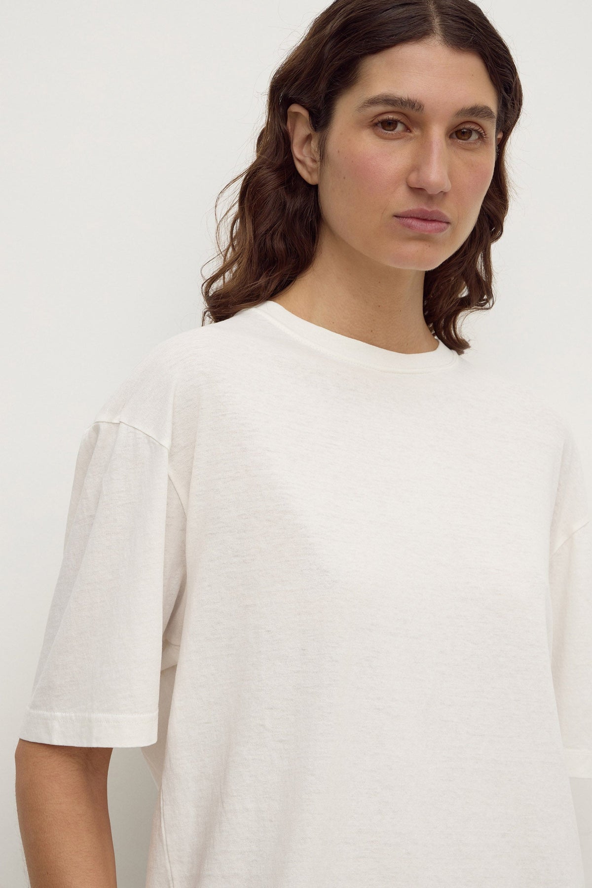 Close-up view of an antique white tee showing the ribbed neckline, short sleeves and relaxed boxy shape.