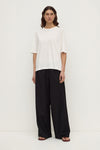 Full front view of a woman wearing an antique white oversized short-sleeve tee with a straight hem and relaxed silhouette.