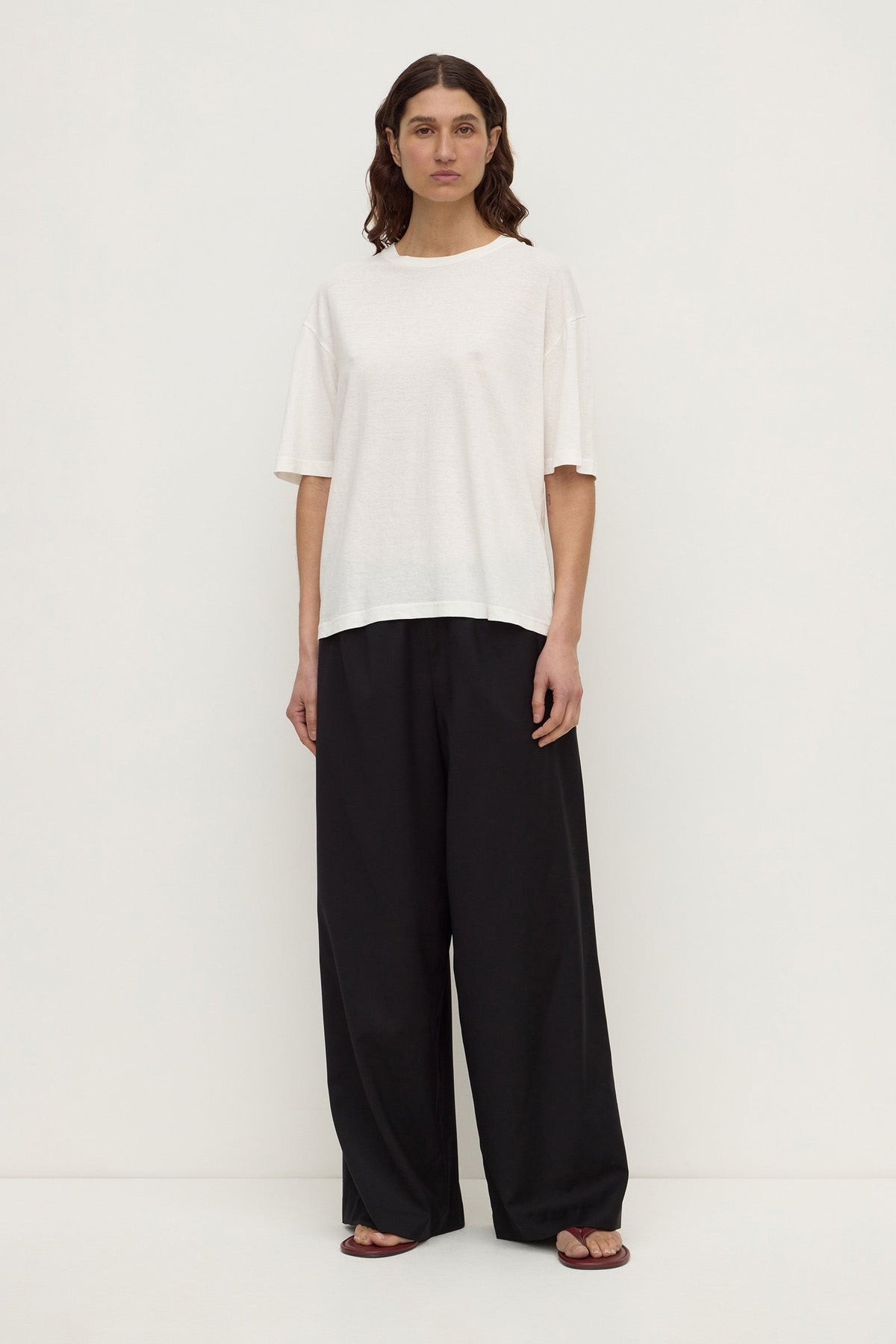 Full front view of a woman wearing an antique white oversized short-sleeve tee with a straight hem and relaxed silhouette.