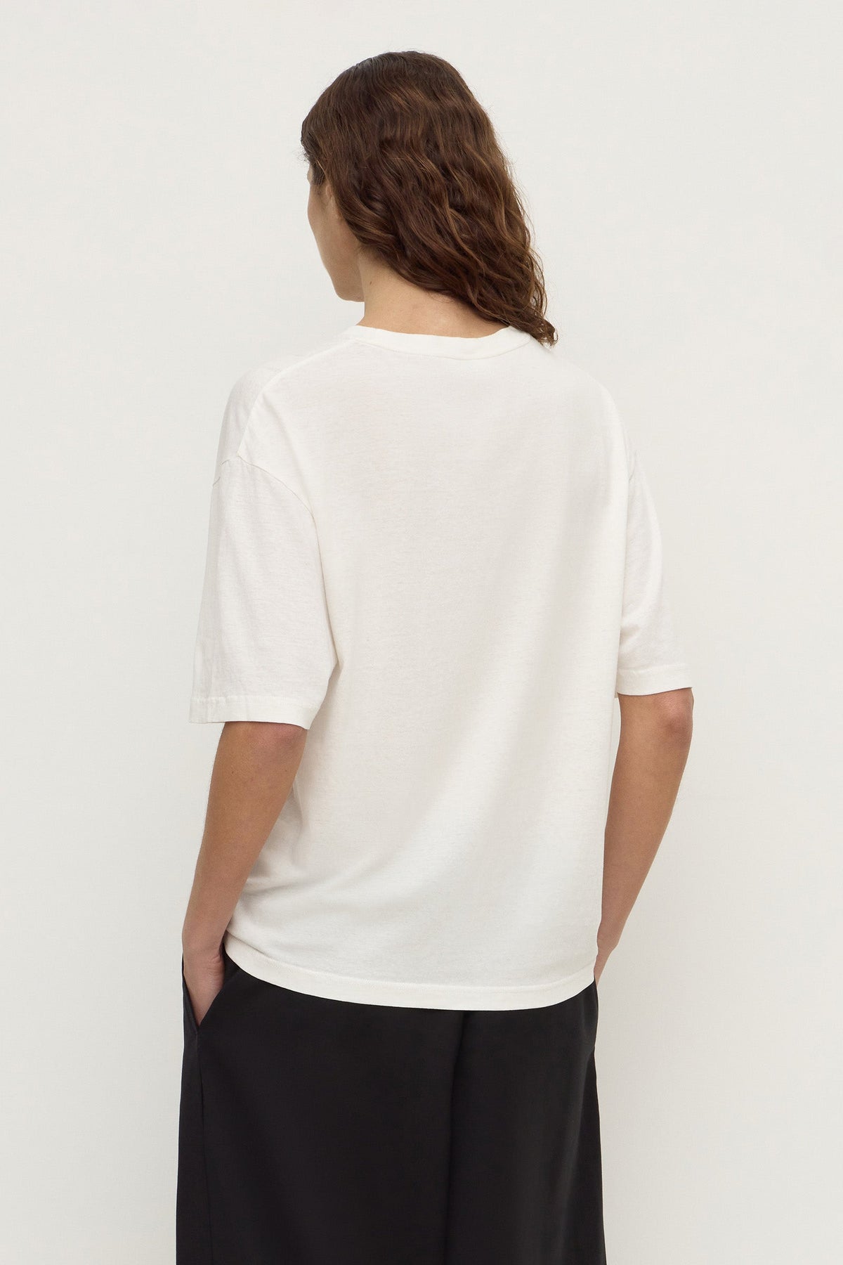 Back view of an antique white short-sleeve tee showing the plain back, relaxed boxy silhouette and straight hem.