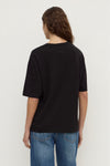 Back view of the black tee showing the ribbed neckline, dropped shoulders, short sleeves and straight hem.