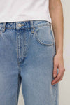 Close-up of the indigo fade jeans showing the waistband, metal button, belt loop, zip fly and curved front pocket stitching.