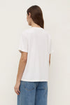 Model wearing the white tee with blue jeans, showing the clean back, relaxed shoulders, short sleeves and hip-length hem, back angled view
