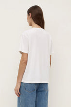 Model wearing the white tee with blue jeans, showing the clean back, relaxed shoulders, short sleeves and hip-length hem, back angled view
