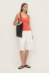 A model wears the dahlia rib tank with a black shoulder bag and white cargo shorts in a three-quarter view.