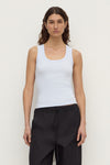 Model wearing a powder blue fitted rib tank with black trousers, showing the scoop neckline and sleeveless silhouette, front view