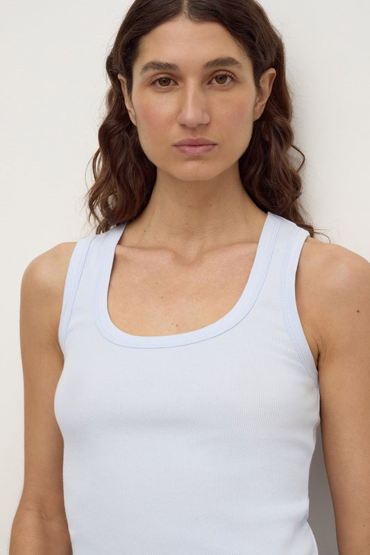 Close-up of model wearing a powder blue fitted rib tank, showing the scoop neckline, wide shoulder straps and ribbed texture