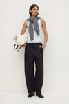 Model wearing a powder blue fitted rib tank with black wide-leg trousers, grey knit draped over the shoulders and a white bag, full-length front view