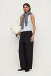 Model wearing a powder blue fitted rib tank with black wide-leg trousers, grey knit draped over the shoulders and a white bag, angled front view