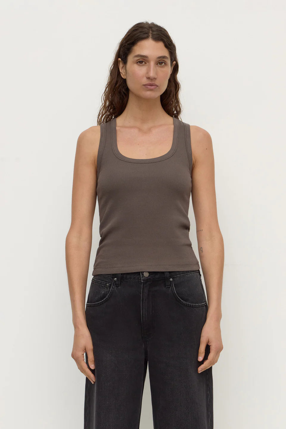 Model wearing the bark rib tank with washed black jeans, showing the scoop neckline, wide shoulder straps, fitted silhouette and hip-length hem, front view
