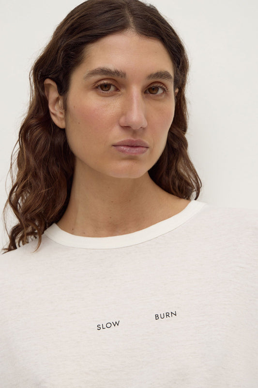 Assembly Label Slow Burn Wide Sleeve Tee in Antique White, close-up showing the ribbed neckline and Slow Burn graphic.
