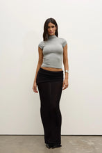 Model wearing a Grey Marle fitted cap-sleeve mock-neck top with a black ruched maxi skirt and pointed shoes, showing the cropped length and slim silhouette, front view