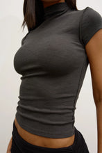 Person wearing a dark gray turtleneck shirt against a plain background