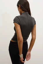 Person wearing a dark gray top and black pants on a white background