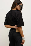Model wearing the black short-sleeve T-shirt with black jeans, showing the dropped shoulders, loose sleeves and relaxed silhouette, back view