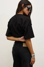 Model wearing the black short-sleeve T-shirt with black jeans, showing the dropped shoulders, loose sleeves and relaxed silhouette, back view