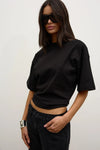 Model wearing the black relaxed-fit short-sleeve T-shirt with black jeans and oversized sunglasses, showing the crew neckline and slightly cropped hem, angled front view