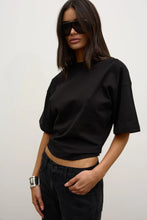 Model wearing the black relaxed-fit short-sleeve T-shirt with black jeans and oversized sunglasses, showing the crew neckline and slightly cropped hem, angled front view