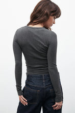 Person wearing a dark gray long-sleeve top and dark jeans on a white background