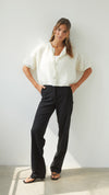 Full-length view of the ivory cardigan styled with black wide-leg trousers, showing its cropped length and short-sleeve design.