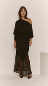 A front view of the black Solene lace skirt styled with an asymmetrical top, showing the flowing satin overlay and sheer floral lace hem.