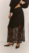 A close-up of the black skirt showing the draped satin overlay, elasticated waistband and sheer floral lace panels.