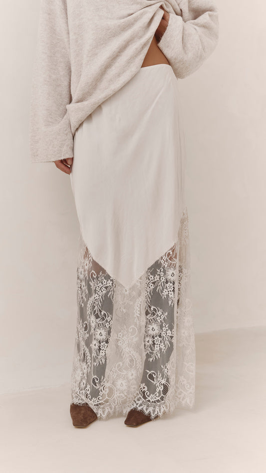 A close-up of the Moonbeam skirt showing its asymmetrical satin overlay and intricate lace hem.