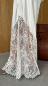 Close-up of the skirt's intricate lace panel and scalloped hem against the satin fabric.