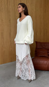 Front view of the Moonbeam skirt styled with a cream V-neck knit, showing its flowing shape and lace-trimmed hem.