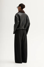 Person wearing a dark green oversized sweater and black pants on a white background