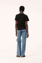 Model wearing the black Zoe Tee with light blue jeans, showing the simple back, relaxed shoulders and boxy silhouette, full-length back view