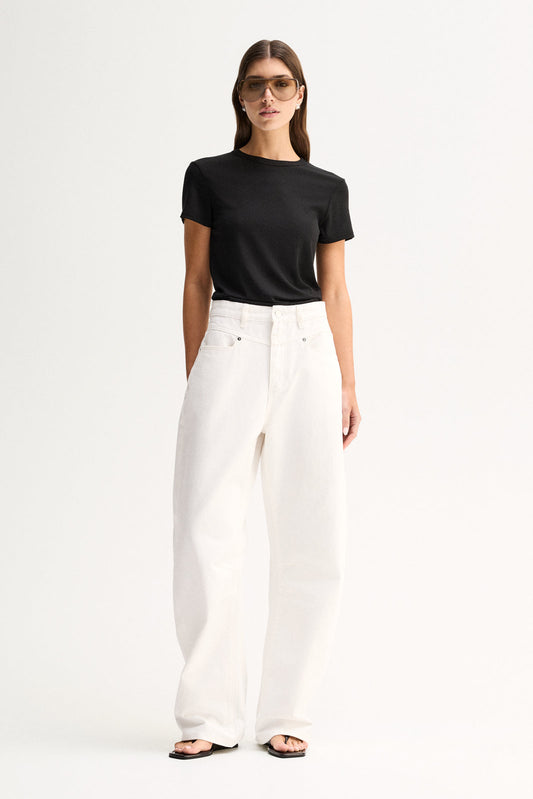 A model wearing a fitted black short-sleeve tee with a round neckline, tucked into white wide-leg trousers and paired with flat black sandals in a full-length front view.