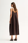 Back three-quarter view showing the chocolate maxi dress with thin straps and a relaxed flowing shape.