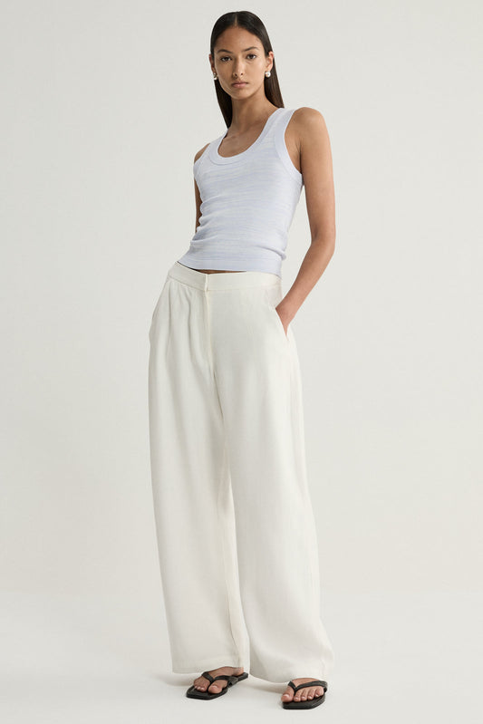 A model wearing a pale blue marled sleeveless knit top with a scoop neckline, paired with cream wide-leg trousers and black flat sandals in a full-length front view.