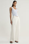A model wearing a pale blue marled knit tank with a scoop neckline and fitted shape, paired with cream wide-leg trousers and black sandals in a relaxed standing pose.