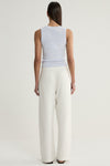 A rear view of a model wearing a pale blue marled sleeveless knit top with a simple back and cream wide-leg trousers, showing the top's fitted shape and hem.