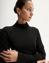 Close-up of model wearing a black fitted long-sleeve top with a high neckline and smooth finish