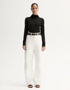 Model wearing a black fitted long-sleeve top with white wide-leg trousers and black sandals, front view