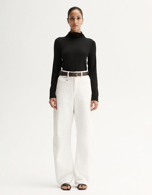 Model wearing a black fitted long-sleeve top with white wide-leg trousers and black sandals, front view