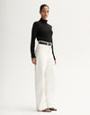 Model wearing a black fitted long-sleeve top with white wide-leg trousers, showing the slim silhouette, angled front view