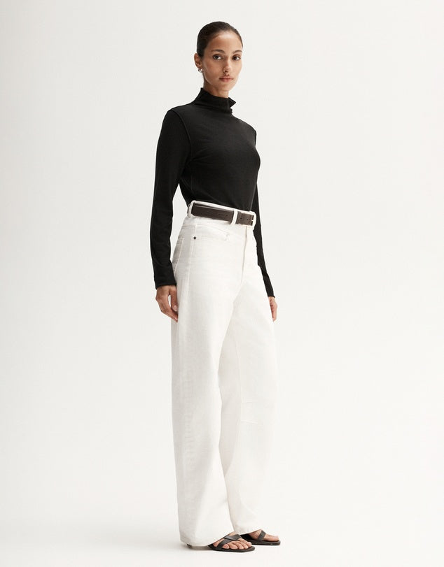 Model wearing a black fitted long-sleeve top with white wide-leg trousers, showing the slim silhouette, angled front view