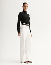 Model wearing a black fitted long-sleeve top with white wide-leg trousers, showing the slim silhouette, angled front view