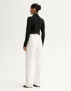 Model wearing a black fitted long-sleeve top with white wide-leg trousers, showing the slim silhouette, angled front view