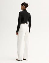 Model wearing a black fitted long-sleeve top with white wide-leg trousers, showing the slim silhouette, angled front view