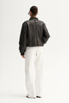 Model wearing the jacket with white wide-leg trousers, back angled view
