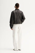 Model wearing the jacket with white wide-leg trousers, back angled view
