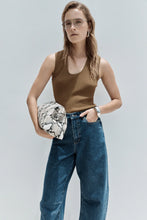 Model wearing the moss Hayes Knit with blue wide-leg jeans and sunglasses, showing the slim fit, sleeveless design, narrow scoop neckline and ribbed texture, lifestyle front view
